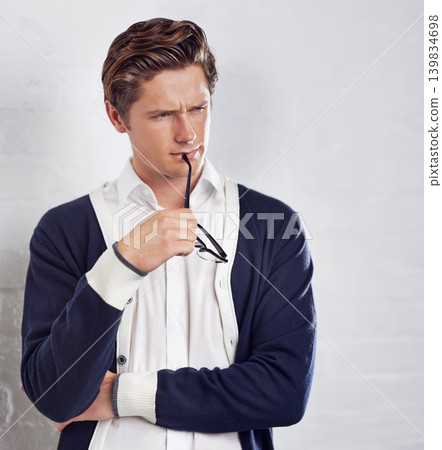 Thinking, fashion and man in studio with confused, doubt or unsure facial expression with glasses. Decision, choice and young male person with style and brainstorming face by gray background. Thinking, fashion and man in studio with confused, doubt or unsure facial expression with glasses. Decision, choice and young male person with style and brainstorming face by gray background. 139834698