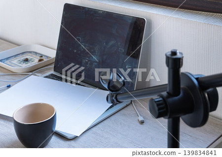 Messy home office workspace with a dirty laptop screen and microphone stand. Blank white paper on computer keyboard. Podcasting or recording studio setup on a wooden desk Messy home office workspace with a dirty laptop screen and microphone stand. Blank white paper on computer keyboard. Podcasting or recording studio setup on a wooden desk 139834841