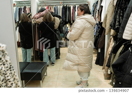 Woman trying on winter coat in clothing store 139834907