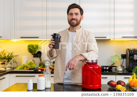 Middle-aged man mixing protein shake in kitchen smiling for fitness diet nutrition workout at home 139835109