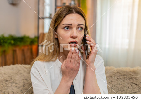 Adult woman talking on smartphone at home, reacting with sympathy concern after receiving bad news Adult woman talking on smartphone at home, reacting with sympathy concern after receiving bad news 139835456