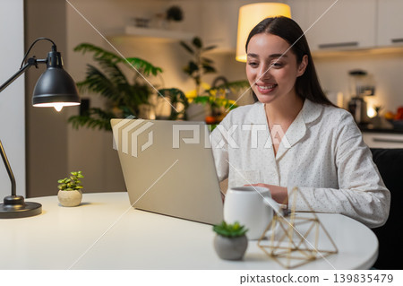 Young woman freelancer opens laptop starts work sharp eyes checks deadlines clicks trackpad evening Young woman freelancer opens laptop starts work sharp eyes checks deadlines clicks trackpad evening 139835479