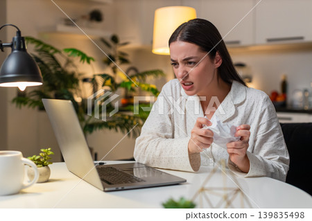 Young woman angry at utility bill crumples receipt throws papers worries about big charges evening Young woman angry at utility bill crumples receipt throws papers worries about big charges evening 139835498