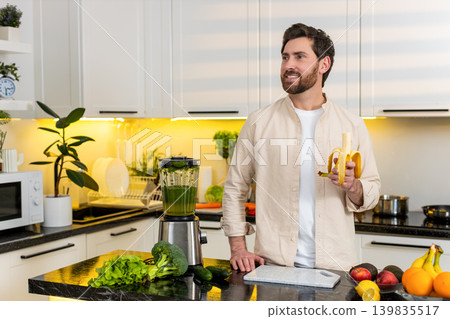 Middle-aged man peeling banana in home kitchen enjoying healthy snack for diet and fitness lifestyle Middle-aged man peeling banana in home kitchen enjoying healthy snack for diet and fitness lifestyle 139835517