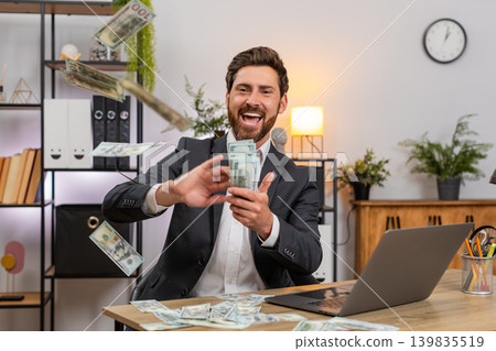 Middle-aged businessman tosses dollar cash makes money rain laughs shares donation with others big Middle-aged businessman tosses dollar cash makes money rain laughs shares donation with others big 139835519