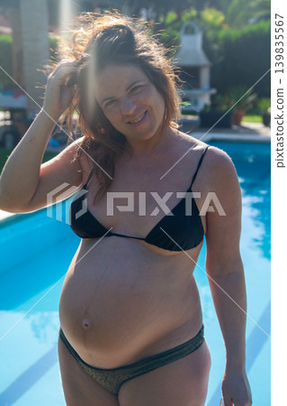 A beautiful woman poses with her pregnant belly A beautiful woman poses with her pregnant belly 139835567