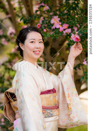 A woman in a kimono smiles as she touches a camellia flower. Kyoto Prefecture, Japan A woman in a kimono smiles as she touches a camellia flower. Kyoto Prefecture, Japan 139835584
