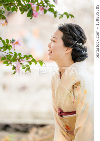 A profile view of a woman in a kimono, smiling as she gazes at flowers. Kyoto Prefecture, Japan. A profile view of a woman in a kimono, smiling as she gazes at flowers. Kyoto Prefecture, Japan. 139835585