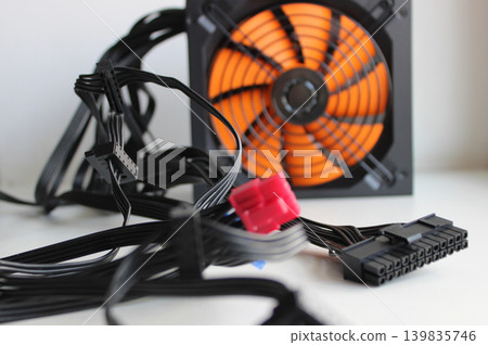 Defocused Fan Blades Of PC Power Supply Behind Wires And Connectors On Foreground Defocused Fan Blades Of PC Power Supply Behind Wires And Connectors On Foreground 139835746