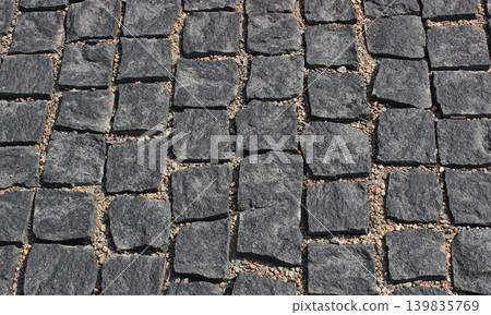Granite paving stones are laid in rows and sprinkled with fine gravel Granite paving stones are laid in rows and sprinkled with fine gravel 139835769