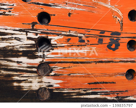 Macro texture of a weathered wooden surface with peeling bright orange paint and cracks. Abstract aged wood with circular holes and distressed marks. Macro texture of a weathered wooden surface with peeling bright orange paint and cracks. Abstract aged wood with circular holes and distressed marks. 139835797
