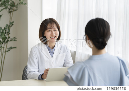 A veteran female doctor conducts a medical interview while holding a tablet. A veteran female doctor conducts a medical interview while holding a tablet. 139836558