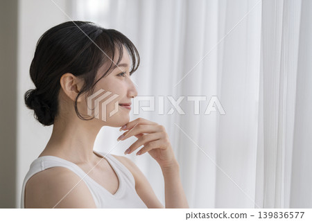 A young woman smiling by the window, profile view. A young woman smiling by the window, profile view. 139836577