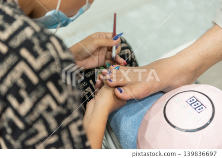 Professional pedicure service colorful nail polish application on toes in beauty salon during foot care treatment Professional pedicure service colorful nail polish application on toes in beauty salon during foot care treatment 139836697