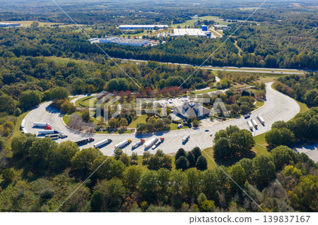 Large truck stop with resting area near busy American interstate freeway. Parking place during big rig interstate travel. Large truck stop with resting area near busy American interstate freeway. Parking place during big rig interstate travel. 139837167