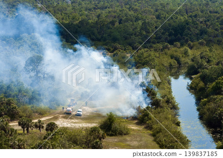 Wild vegetation fire spreads across forested landscape in Florida, with firefighters working in heavy smoke and intense heat to control the flames during dry season 139837185