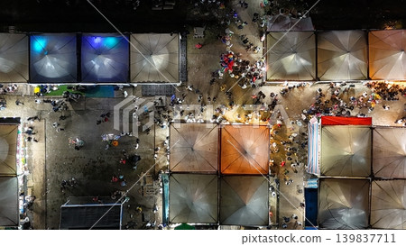An aerial top-down view of a vibrant night market and amusement park illuminated by colorful neon lights. An aerial top-down view of a vibrant night market and amusement park illuminated by colorful neon lights. 139837711