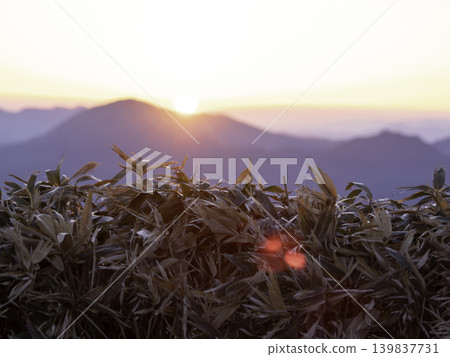 日出的瞬間。美麗的太陽和晨曦從遠處的山峰升起。 日出的瞬間。美麗的太陽和晨曦從遠處的山峰升起。 139837731