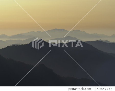 Mountain ranges floating in the morning mist. Layers of ridgelines and a beautiful gradient of sunrise. Mountain ranges floating in the morning mist. Layers of ridgelines and a beautiful gradient of sunrise. 139837752