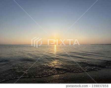 A scene of the setting sun reflecting on calm waves. A scene of the setting sun reflecting on calm waves. 139837858