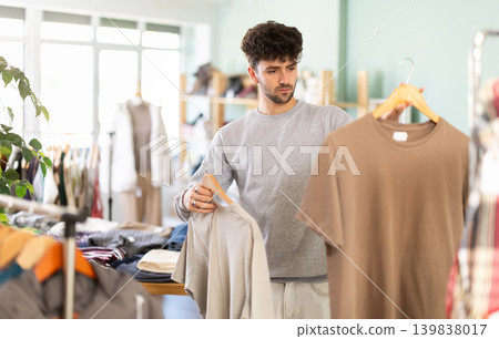 Bearded young man choosing t-shirts in fashion boutique 139838017