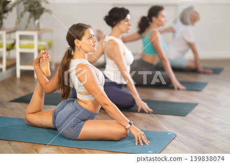 Girl performing one legged King Pigeon Pose at group yoga session Girl performing one legged King Pigeon Pose at group yoga session 139838074