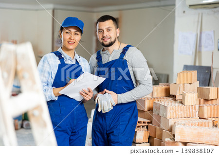 Smiling female foreman and bearded worker with papers at construction site Smiling female foreman and bearded worker with papers at construction site 139838107