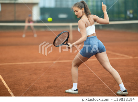Young woman making serve while playing tennis 139838194