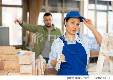 Confused female builder in building under construction with angry customer Confused female builder in building under construction with angry customer 139838195