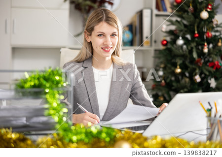 Female office worker sitting at her workplace during Christmastime Female office worker sitting at her workplace during Christmastime 139838217