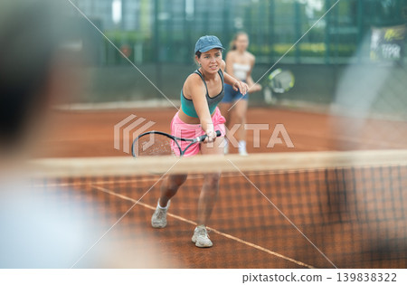 Sporty young girl playing doubles tennis on outdoor court Sporty young girl playing doubles tennis on outdoor court 139838322