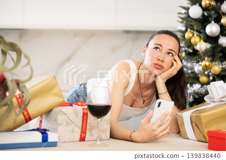 pensive young girl stands among New Year s gifts pensive young girl stands among New Year s gifts 139838440