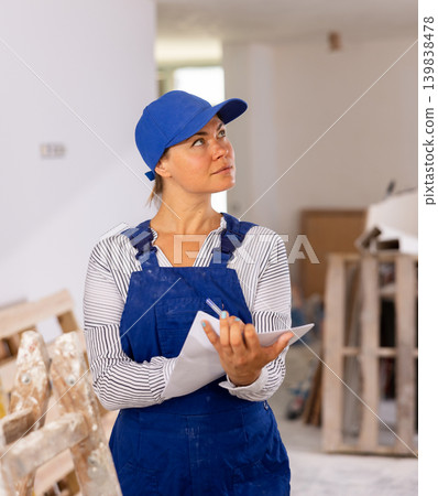 Woman in blue overalls checking completed construction work on drawing Woman in blue overalls checking completed construction work on drawing 139838478