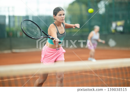 Focused girl playing doubles tennis on outdoor court Focused girl playing doubles tennis on outdoor court 139838515