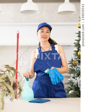 young positive girl is cleaning kitchen after New Year s party young positive girl is cleaning kitchen after New Year s party 139838541