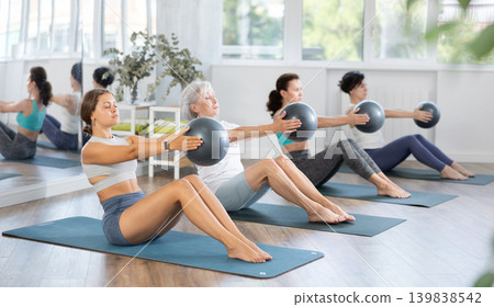Young woman doing pilates with soft ball in group Young woman doing pilates with soft ball in group 139838542