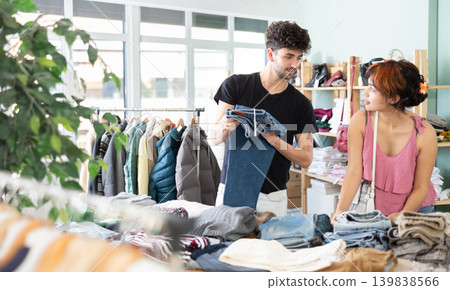 Couple spend time in shop and chooses jeans trousers Couple spend time in shop and chooses jeans trousers 139838566