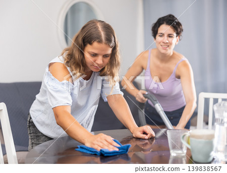 Young female couple cleaning living room together Young female couple cleaning living room together 139838567