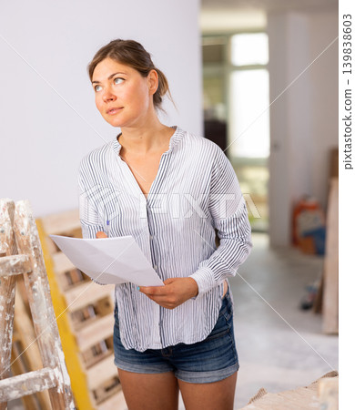 Woman designer checking documents during repair works Woman designer checking documents during repair works 139838603