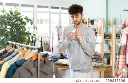 Guy try on sweater in front of mirror in clothes store Guy try on sweater in front of mirror in clothes store 139838606