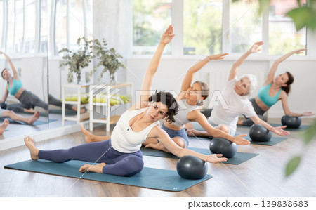 Adult woman doing pilates with soft ball in group 139838683