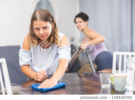 Young female couple cleaning living room together Young female couple cleaning living room together 139838708