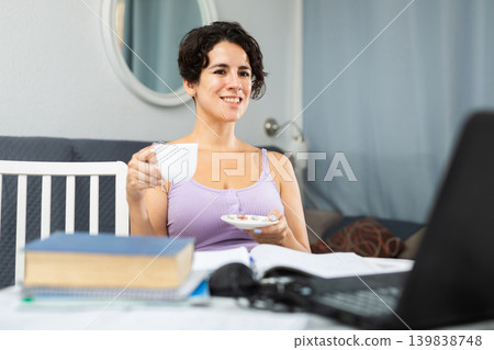 Relaxed brunette drinking tea and looking for something on Internet Relaxed brunette drinking tea and looking for something on Internet 139838748