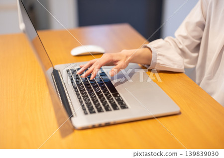 A close-up of a woman's hands typing on a laptop keyboard. A close-up of a woman's hands typing on a laptop keyboard. 139839030