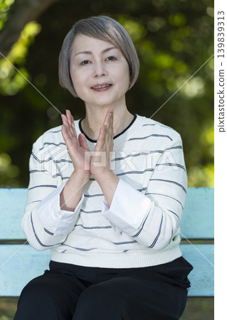 Senior women watching sports on a park bench surrounded by fresh greenery. 139839313