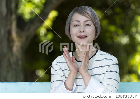 Senior women watching sports on a park bench surrounded by fresh greenery. Senior women watching sports on a park bench surrounded by fresh greenery. 139839317