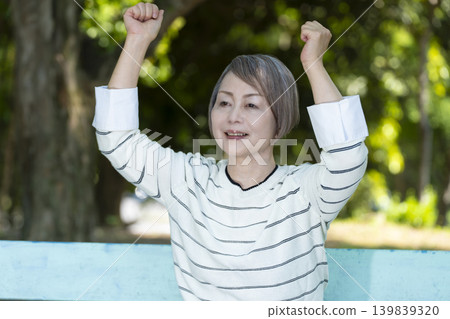 Senior women watching sports on a park bench surrounded by fresh greenery. 139839320