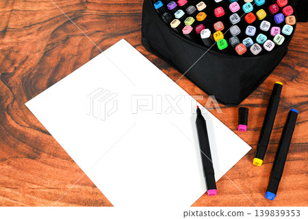 vertical sheet of white paper with colored sketch markers on wooden table vertical sheet of white paper with colored sketch markers on wooden table 139839353