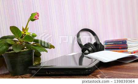 laptop from the side on a desk next to a houseplant and headphones 139839364