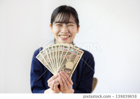 The woman holds ten 10,000 yen bills in her hand. The woman holds ten 10,000 yen bills in her hand. 139839658